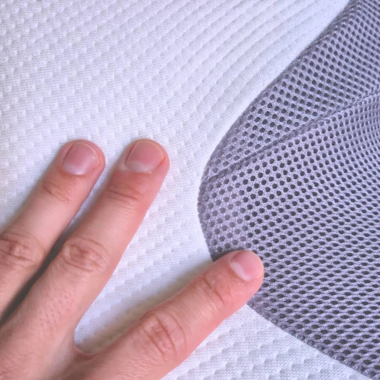 Hand holding a gray mesh fabric against a white background