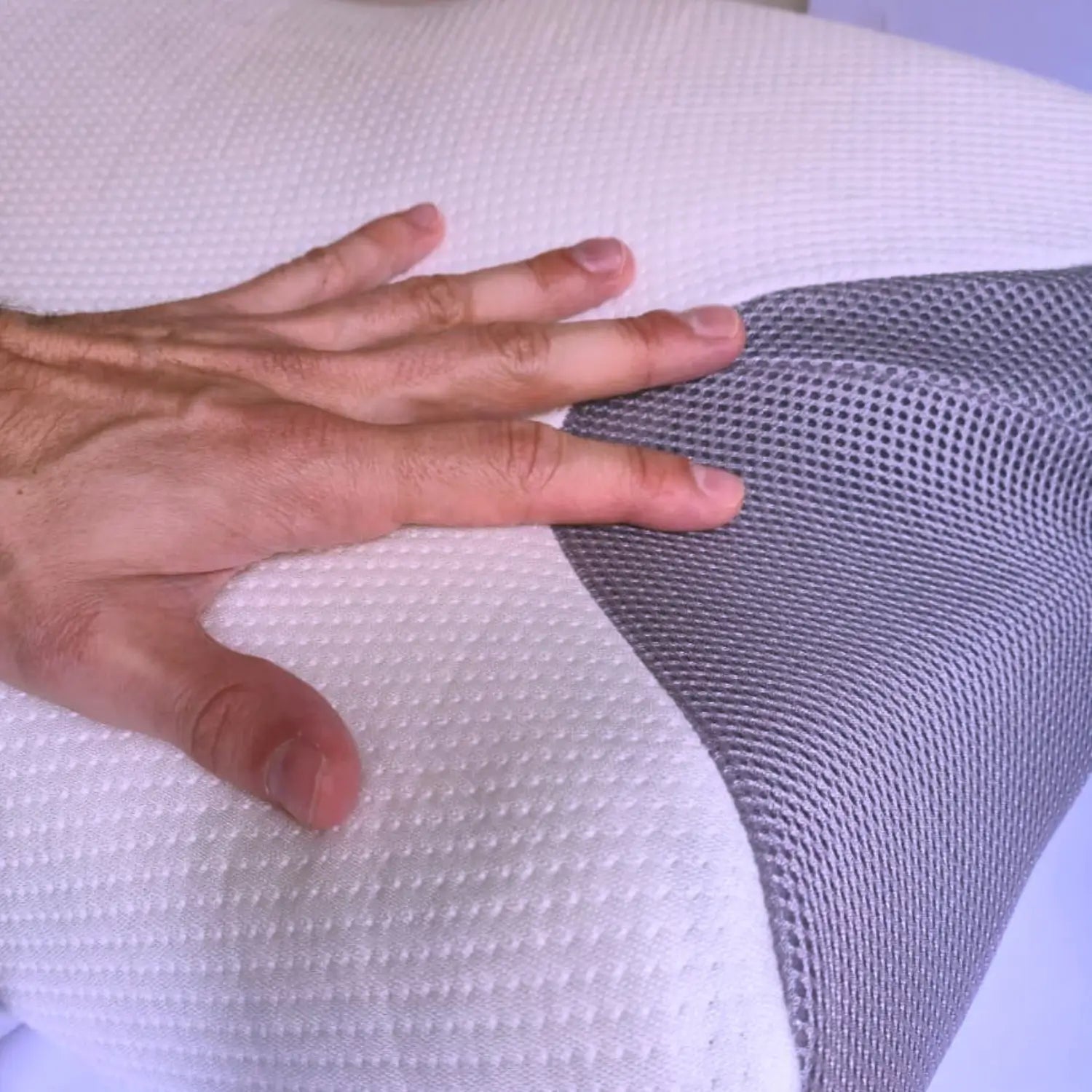 Hand pressing onto a white and gray textured pillow